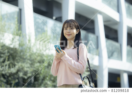 A woman looking at a smartphone outdoors 81209818