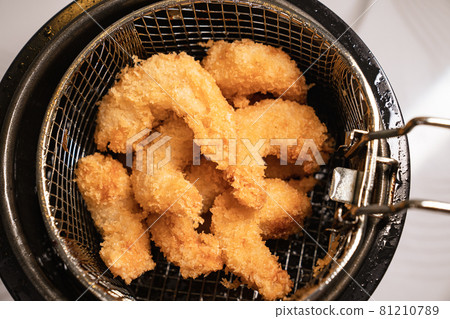 from the fryer pull out a basket with fried shrimp in batter. from the fryer pull out a basket with fried shrimp in batter. 81210789