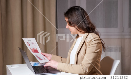 Young woman hands type on grey laptop keyboard and looks at graphs 81211282