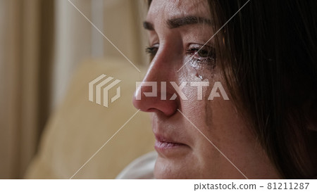Close-up of a crying young woman with blurry mascara dripping down her cheeks Close-up of a crying young woman with blurry mascara dripping down her cheeks 81211287