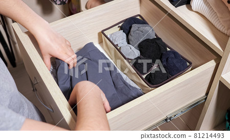 Woman chooses socks in drawer of large cabinet in room Woman chooses socks in drawer of large cabinet in room 81214493