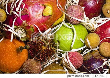 Different tropical fruits in gift box on wooden table. Different tropical fruits as background, closeup view. Different tropical fruits in gift box on wooden table. Different tropical fruits as background, closeup view. 81214602