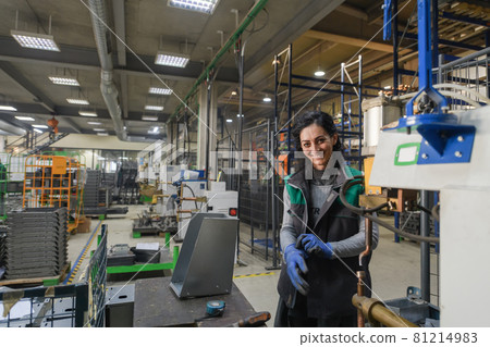 a woman working in a modern metal factory assembles parts for a new machine 81214983
