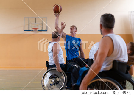 handicapped war veterans in wheelchairs with professional equipment play basketball match in the hall.the concept of sports with disabilities handicapped war veterans in wheelchairs with professional equipment play basketball match in the hall.the concept of sports with disabilities 81214984