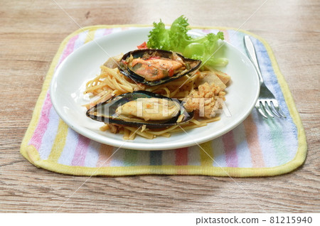 fried spicy seafood spaghetti with basil leaf topping mussel dressing chili sauce on plate 81215940