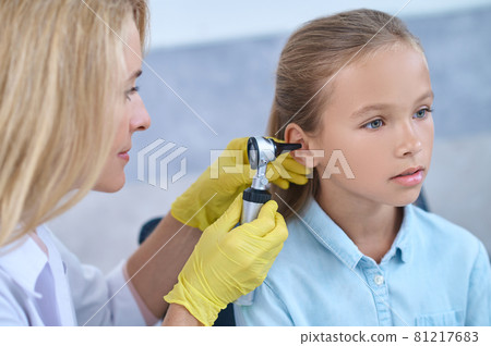 Otolaryngologist with otoscope near ear of little girl Otolaryngologist with otoscope near ear of little girl 81217683