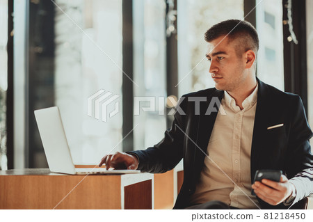 Happy business man sitting at cafeteria with laptop and smartphone Happy business man sitting at cafeteria with laptop and smartphone 81218450