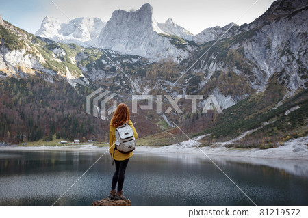 girl stands on the shore of a mountain lake 81219572