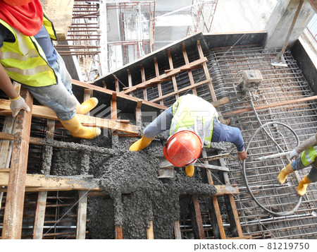 SELANGOR, MALAYSIA -AUGUST 01, 2016: Group of construction workers pouring wet concrete using concrete bucket into the timber form work at the construction site.   81219750