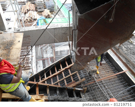 SELANGOR, MALAYSIA -AUGUST 01, 2016: Group of construction workers pouring wet concrete using concrete bucket into the timber form work at the construction site.   81219751