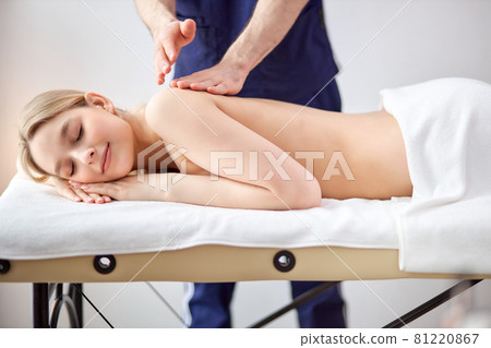 Gorgeous lady lying on tummy receiving massage on back by cropped male therapist 81220867
