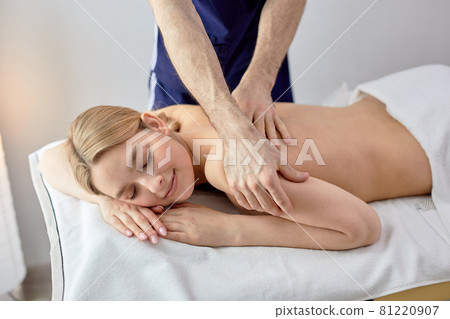 Young blonde woman receiving back massage from cropped male masseur in spa center Young blonde woman receiving back massage from cropped male masseur in spa center 81220907