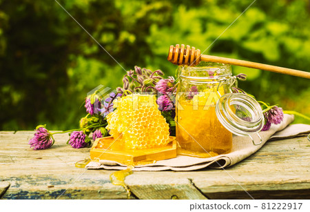 Fresh honey in a glass jar on a summer rural background. Floral fragrant sweet honey dessert, front view  81222917