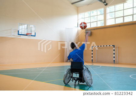 a war invalid in a wheelchair trains with a ball at a basketball club in training with professional sports equipment for the disabled. the concept of sport for people with disabilities 81223342