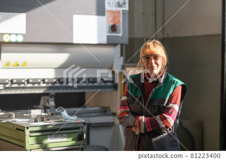 portrait of a woman standing in front of a CNC machine in goggles and working in a modern metal production and processing factory portrait of a woman standing in front of a CNC machine in goggles and working in a modern metal production and processing factory 81223400