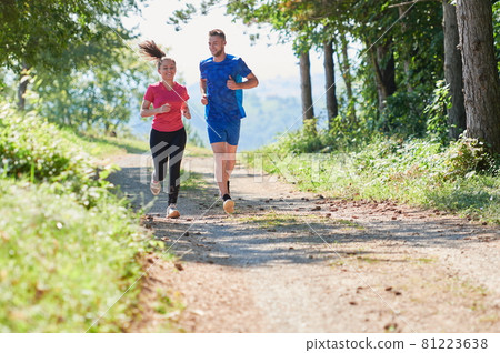 couple enjoying in a healthy lifestyle while jogging on a country road couple enjoying in a healthy lifestyle while jogging on a country road 81223638