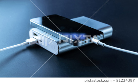 Phone power bank. Mobile phone or smartphone battery charging from portable powerbank with white usb cable. External battery for mobile devices. Phone power bank. Mobile phone or smartphone battery charging from portable powerbank with white usb cable. External battery for mobile devices. 81224397