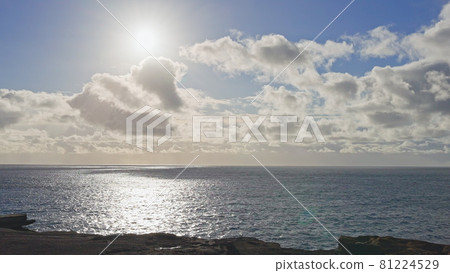 Sunrise over the island of Oahu. White clouds float across the blue sky. Blue Waves of the Pacific Ocean Beats Oahu Island Volcanic Cliffs. Turquoise water color. Clear sunny day. DCI 4k 81224529