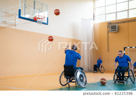 a war invalid in a wheelchair trains with a ball at a basketball club in training with professional sports equipment for the disabled. the concept of sport for people with disabilities 81225396