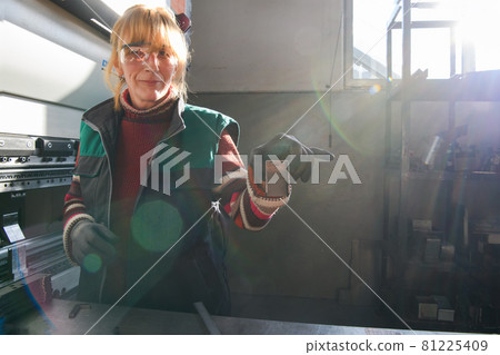 woman working in a modern factory and preparing materia for a CNC machine. woman working in a modern factory and preparing materia for a CNC machine. 81225409