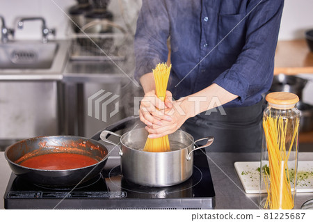 一個穿著圍裙煮意大利面的年輕人的手烹飪男孩形象 81225687