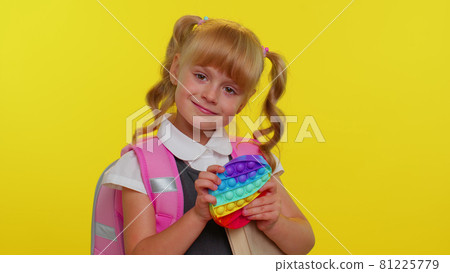 Joyful pupil girl playing with pop it sensory anti-stress toy kid presses on squishy bubbles game 81225779