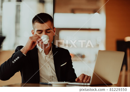 Happy business man sitting at cafeteria with laptop and smartphone Happy business man sitting at cafeteria with laptop and smartphone 81229350