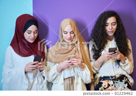 Muslim women using mobile phones isolated on blue and purple background 81229462