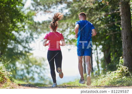 couple enjoying in a healthy lifestyle while jogging on a country road 81229587