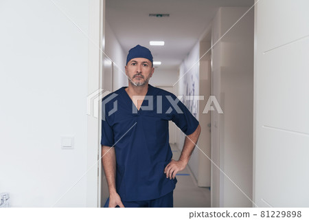 Portrait Of Mature Male Doctor In Busy Modern Hospital Corridor.  81229898
