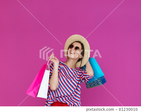 Young woman with shopping bags on pink background 81230010