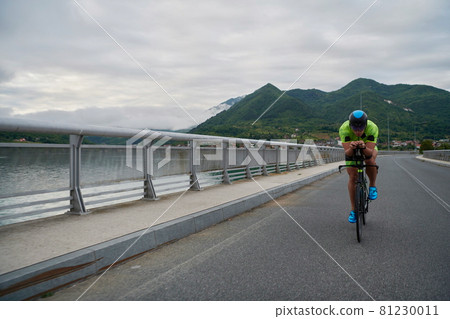 triathlon athlete riding a bike on morning training triathlon athlete riding a bike on morning training 81230011