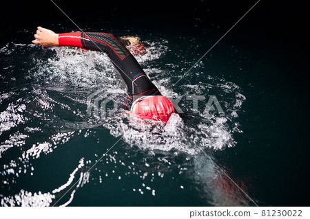 triathlon athlete swimming in dark night wearing wetsuit 81230022