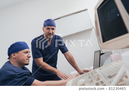 Orthopedist doctor team examining digital X-ray picture in clinic on a laptop computer Orthopedist doctor team examining digital X-ray picture in clinic on a laptop computer 81230465