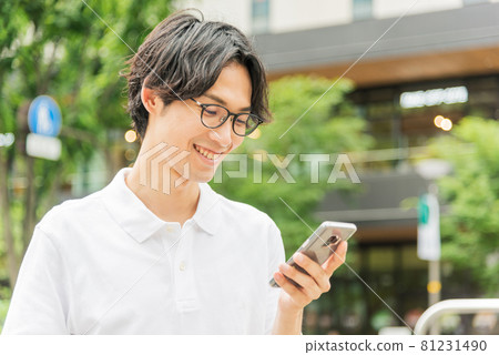 A young man operating a smartphone in the city 81231490