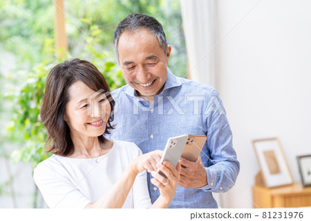 Senior couple looking at a smartphone in the living room 81231976