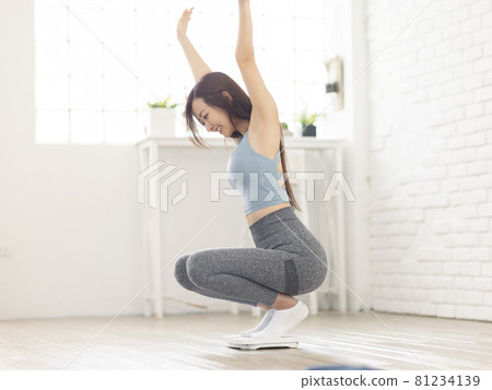 Excited woman sitting on scales at home overjoyed Excited woman sitting on scales at home overjoyed 81234139