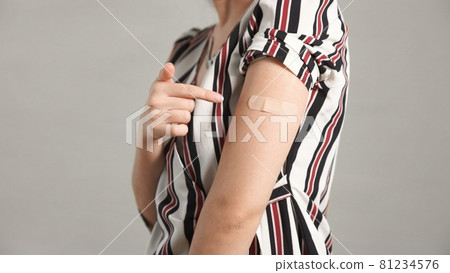 Young woman showing COVID-19 vaccine bandage merrily 81234576