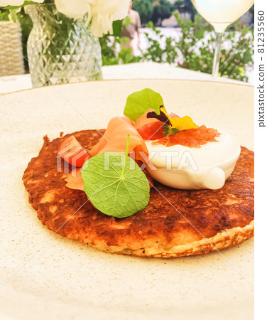 Potato fritter pancake with red caviar, salmon and sour cream in luxury restaurant outdoors in summer 81235560