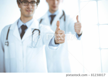 Two male doctors standing as a team and showing thumbs up as a symbol of the best service for patients in the clinic. Medicine and health care Two male doctors standing as a team and showing thumbs up as a symbol of the best service for patients in the clinic. Medicine and health care 81238017