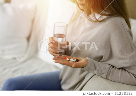 Close-up woman holding pills time to take medications, cure for headache. Medicine concept during self isolation and Coronavirus pandemic 81238152