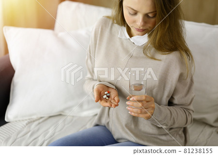 Close-up woman holding pills time to take medications, cure for headache. Medicine concept during self isolation and Coronavirus pandemic 81238155