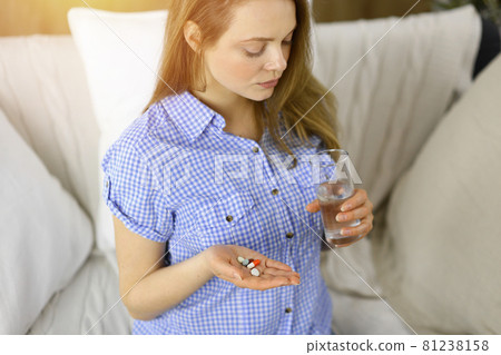 Close-up woman holding pills time to take medications, cure for headache. Medicine concept during self isolation and Coronavirus pandemic 81238158