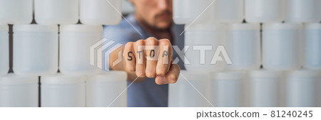 BANNER, LONG FORMAT Man showing stop surrounded by many jars of yoghurt that he uses in a year. A huge amount of plastic food jars. Excessive consumption of plastic. Reduce, reuse, recycle 81240245