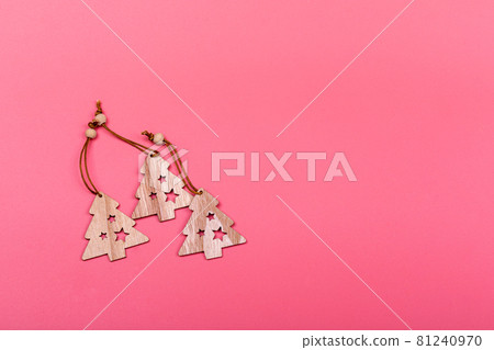 New Year and Christmas wooden toys on pink background. Laser cut wooden Christmas tree figurines. Postcard composition with free space for text. New Year and Christmas concept. 81240970