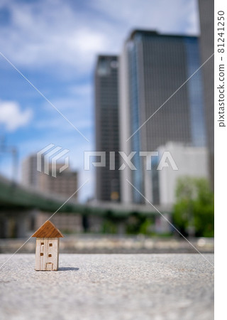 A small wooden house with urban buildings in the background 81241250