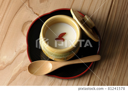 A bird's-eye view of almond tofu in a mini jar with goji berries and a wooden spoon 81241578