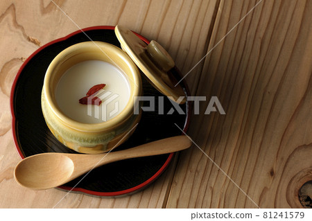 A bird's-eye view of almond tofu in a mini jar with goji berries and a wooden spoon 81241579
