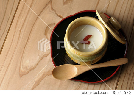 A bird's-eye view of almond tofu in a mini jar with goji berries and a wooden spoon 81241580