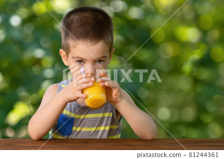 little boy drinking orange juice from glass little boy drinking orange juice from glass 81244361